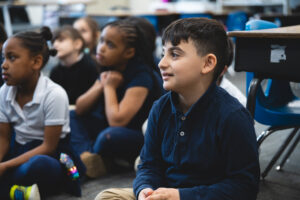 Students sitting down on the carpet